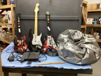 PS2 CONSOLE, (3) VIDEO GAME GUITARS AND SET OF DRUMSTICKS, WIRELESS CONTROLLER, BEAN BAG