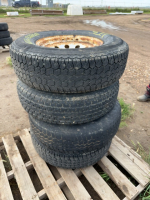 Stack of four trailer tires on rims
