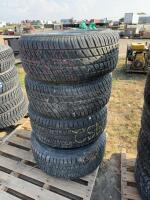 Stack of four mismatched tires on rims