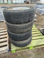 Stack of four car tires on Chevrolet rims