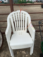 Stack of four white plastic chairs